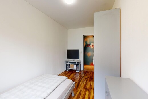 zimmer / schlafzimmer mit drywall, gipskartonwand, wood finish floor, holzfußboden, und fernseher