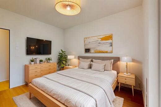 zimmer / schlafzimmer mit fernseher, gipskartonwand, drywall, holzfußboden, und wood finish floor