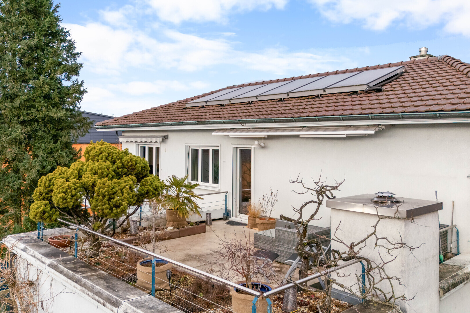 outdoor house with roof mounted solar panels, stucco siding, a tiled roof, a patio area, and outdoor dining space