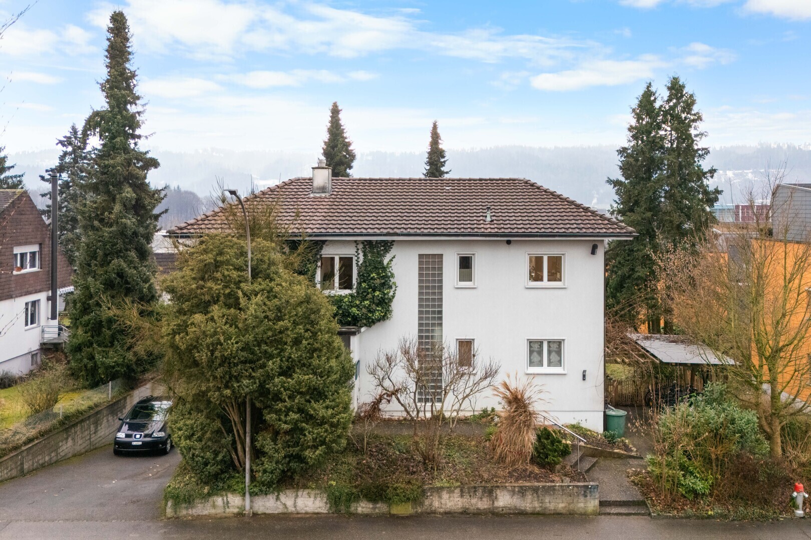 view of home featuring a chimney, stucco siding, and a tiled roof