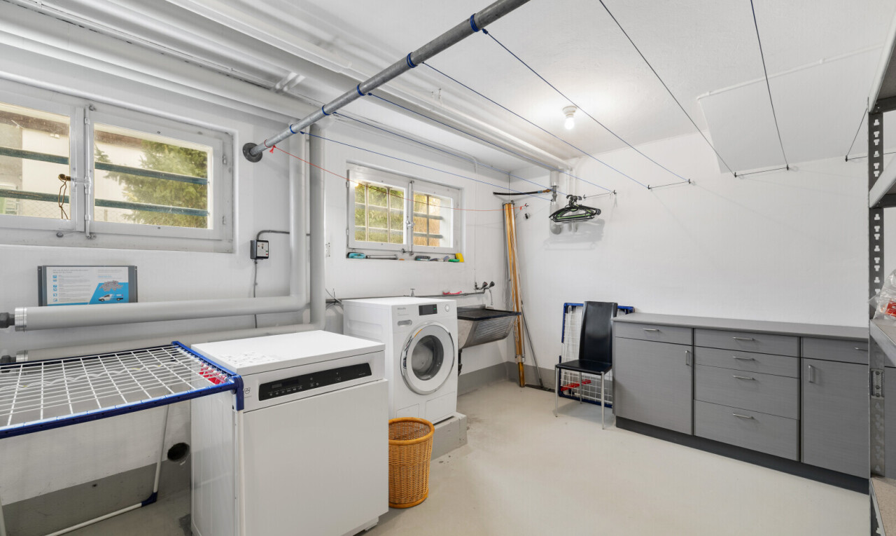 buanderie avec cloison sèche, drywall, lave-linge et sèche-linge, sol en béton, et concrete floor