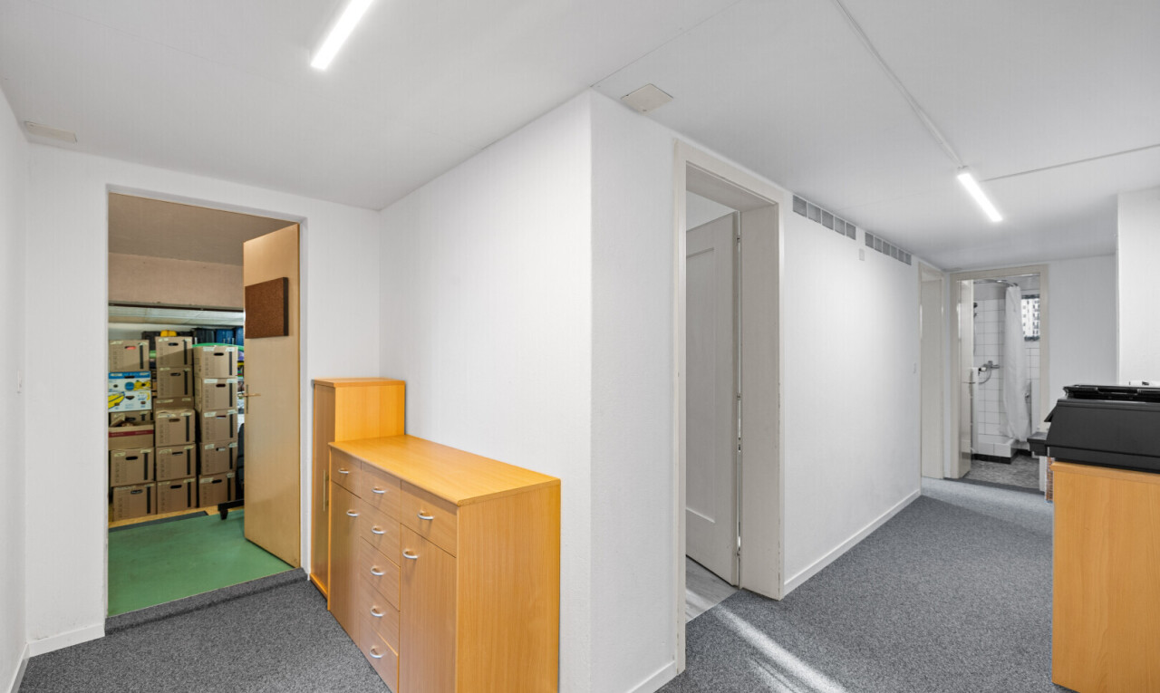 corridor featuring dark colored carpet and baseboards