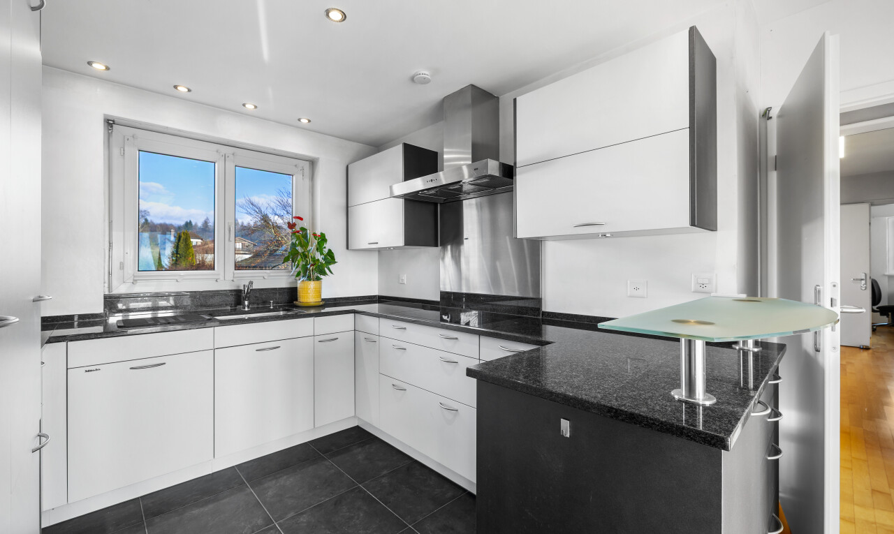 cuisine avec dark floor, dark countertops, hotte, armoires blanches, et white cabinets