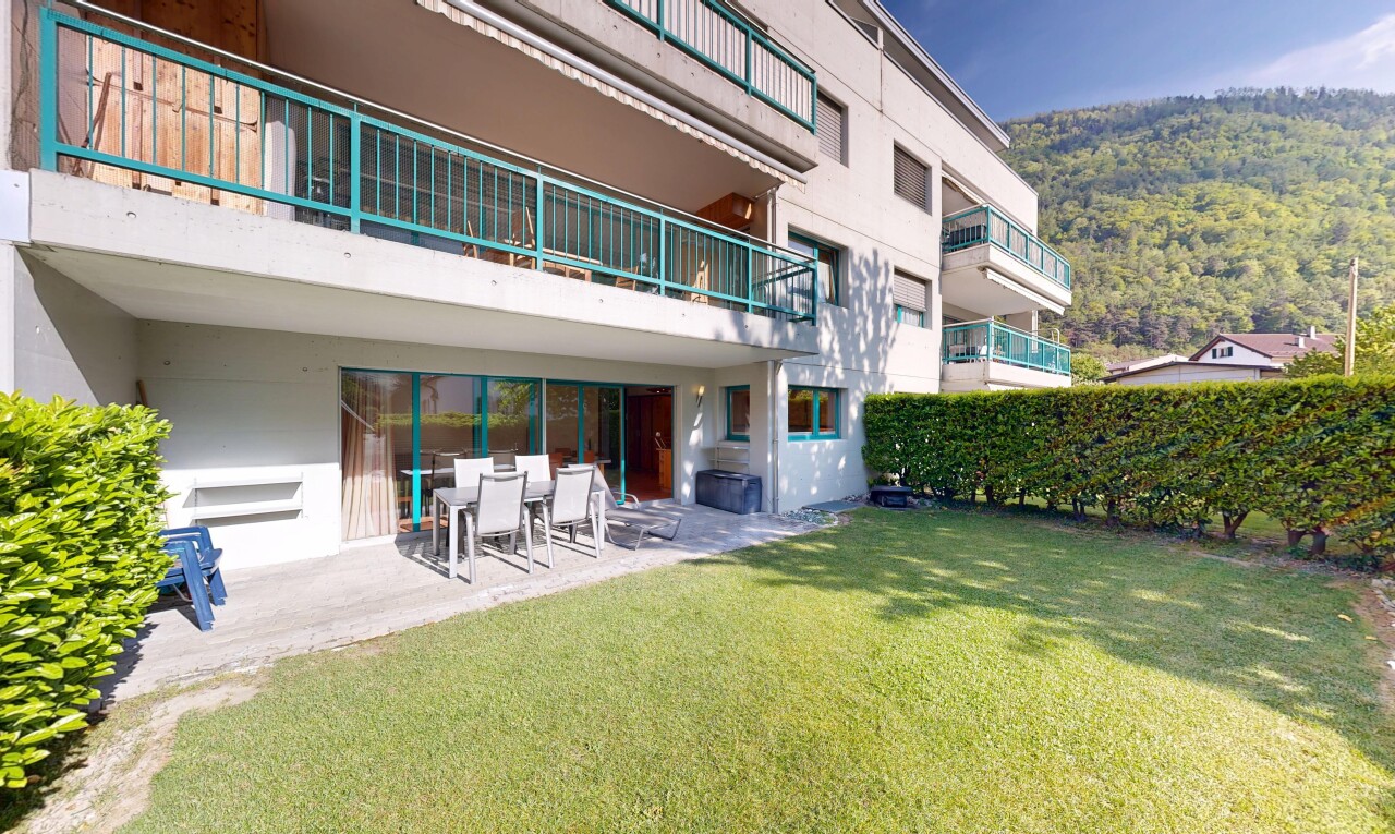 view of property with a balcony, a patio, a yard, outdoor dining area, and stucco siding
