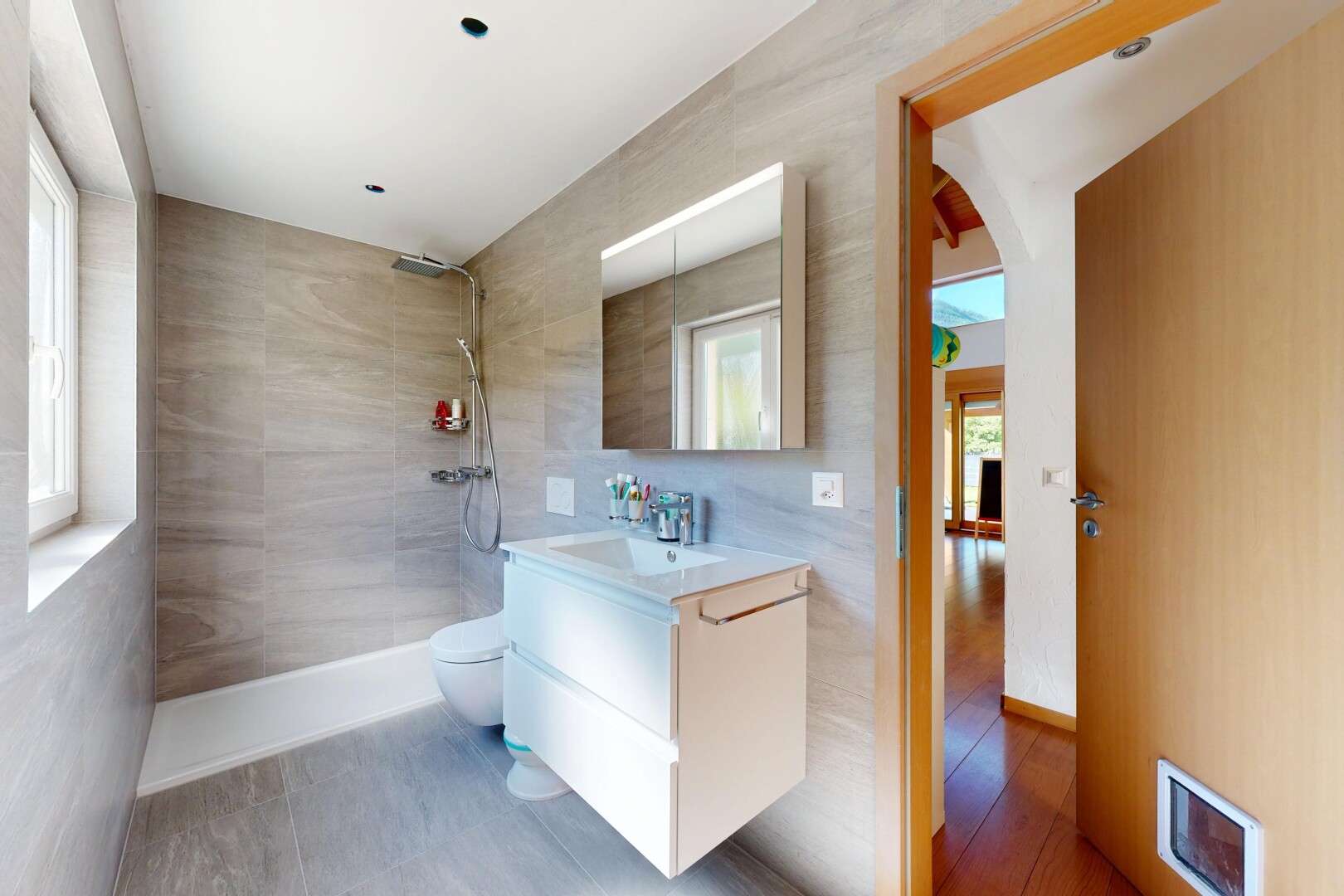 full bathroom featuring walk in shower, vanity, and tile walls