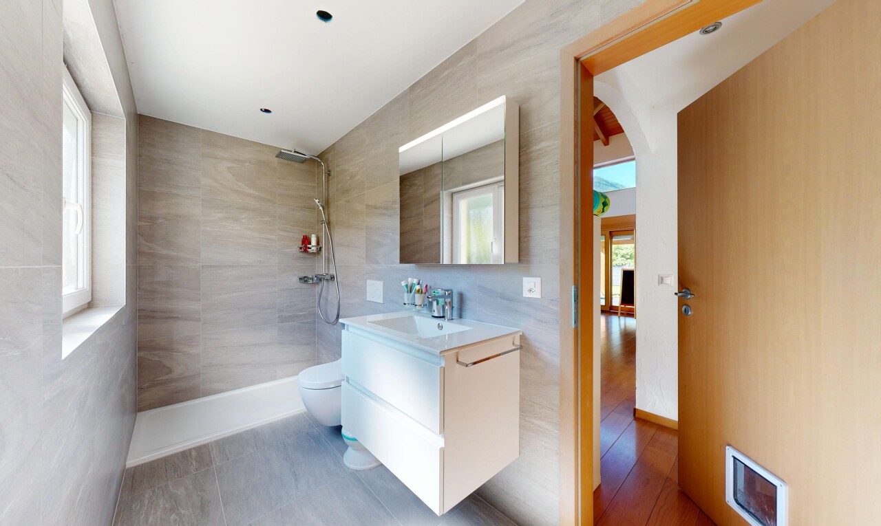 full bathroom featuring walk in shower, vanity, and tile walls