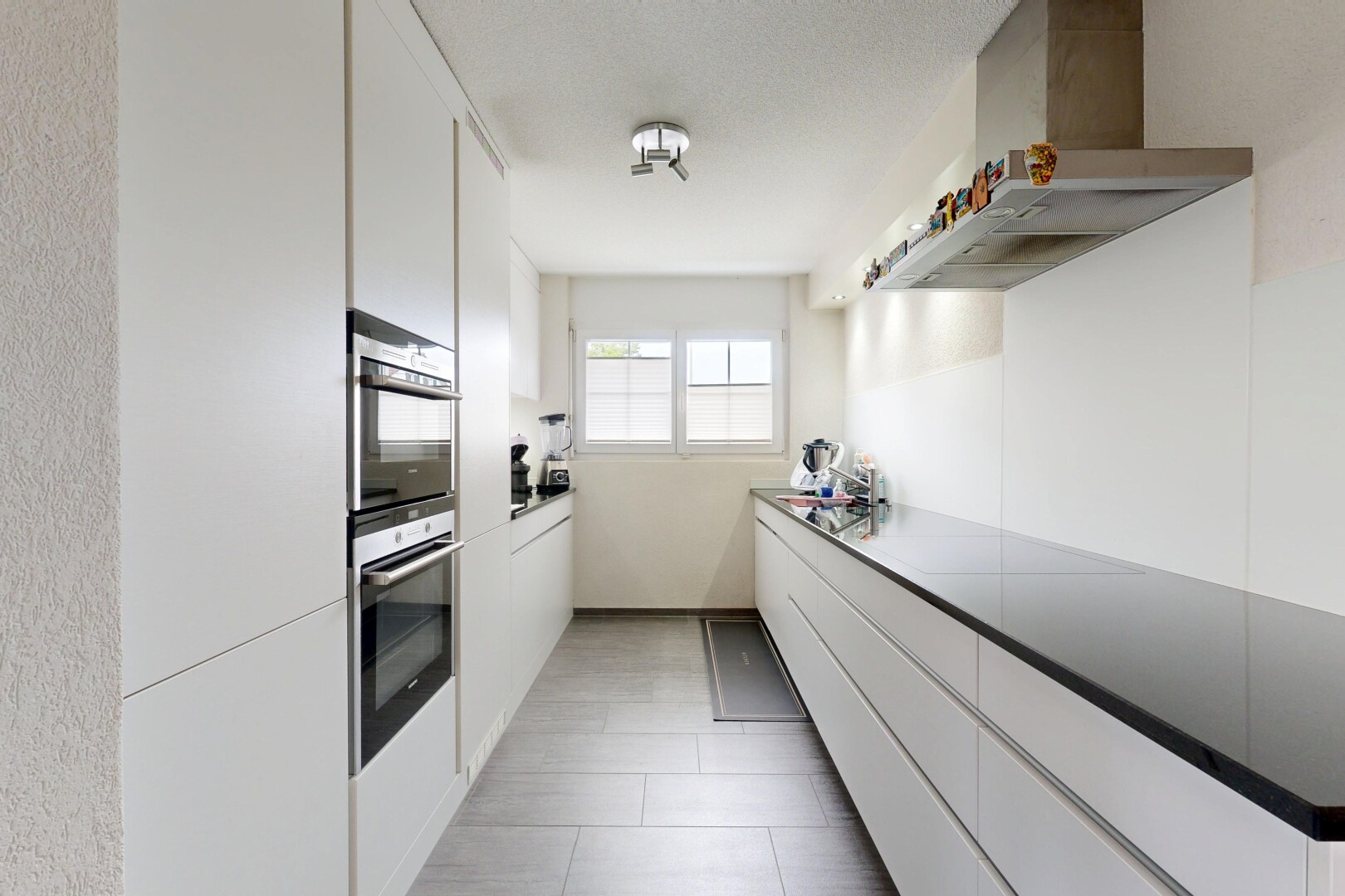 kitchen with white cabinets, wall chimney exhaust hood, double oven, modern cabinets, and light tile patterned floors