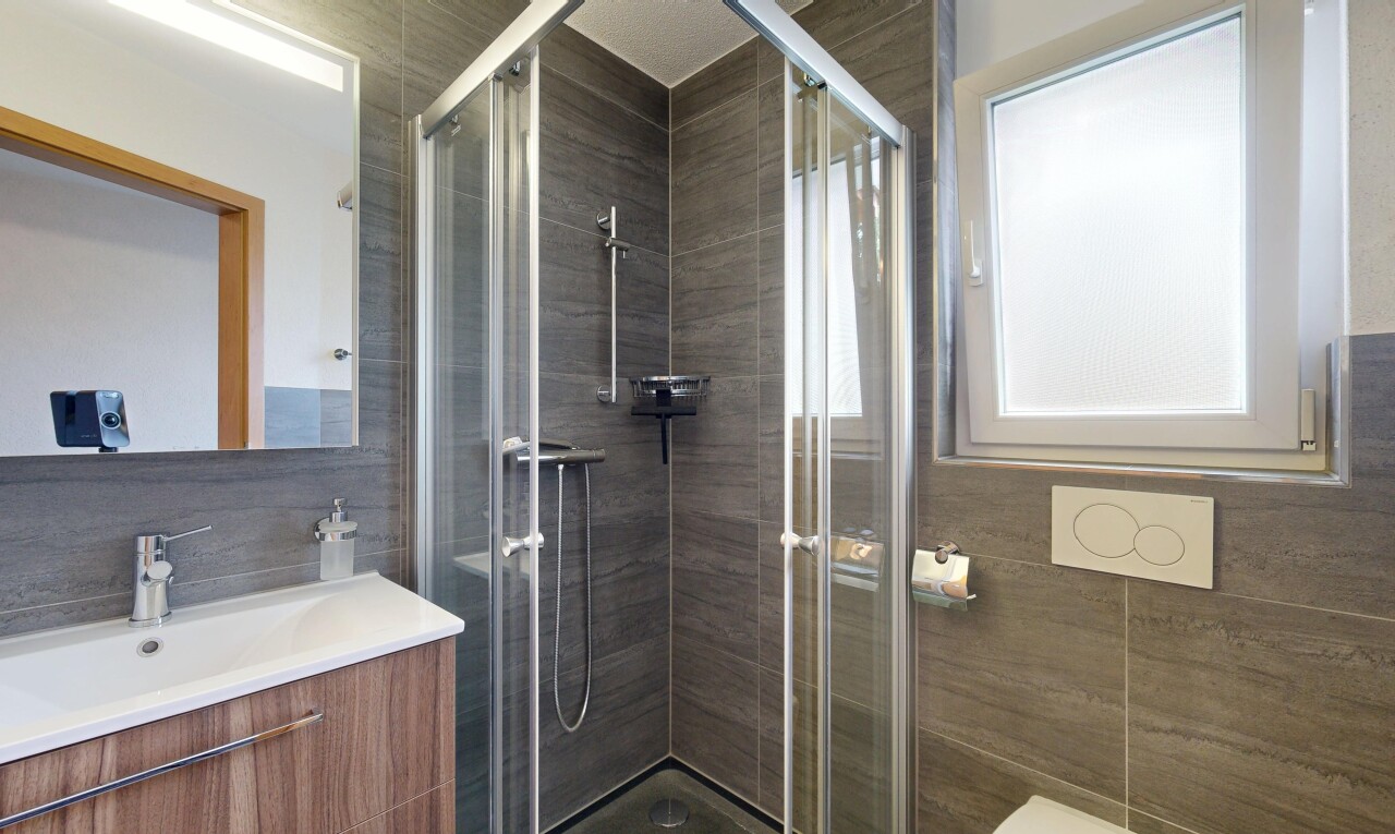 bathroom with vanity, a shower stall, and tile walls