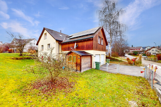 außenansicht mit zaun, eingebaute garage, solaranlage, und rasen