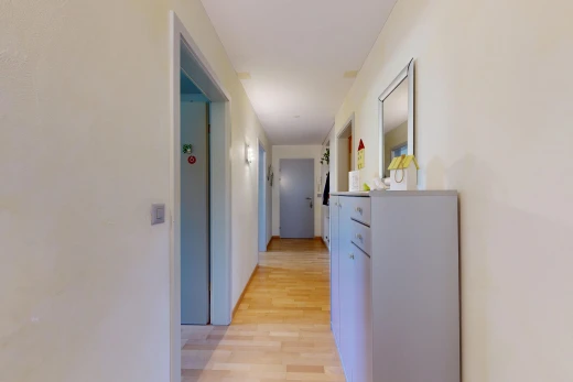 couloir avec light floor, cloison sèche, drywall, sol en finition bois, et wood finish floor