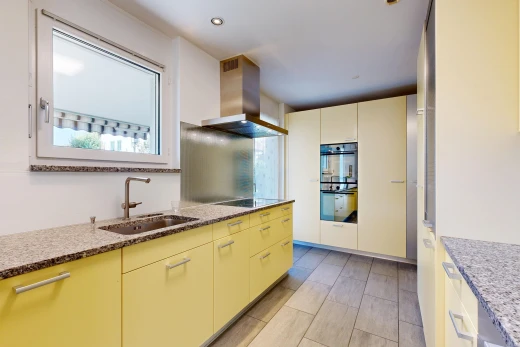 cuisine avec hotte, light floor, plans de travail en pierre, stone countertops, et évier