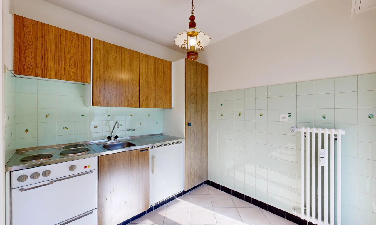 cuisine avec radiateur, light countertops, plans de travail, medium brown cabinets, et armoires marron moyen