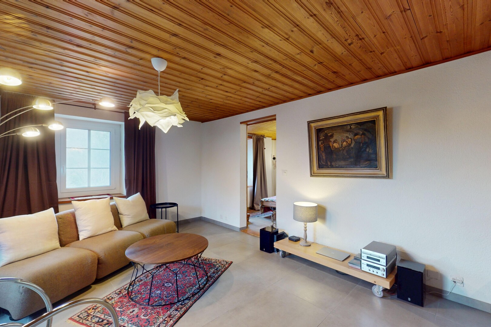salon avec lumière naturelle, plafond de bois, et sol en béton