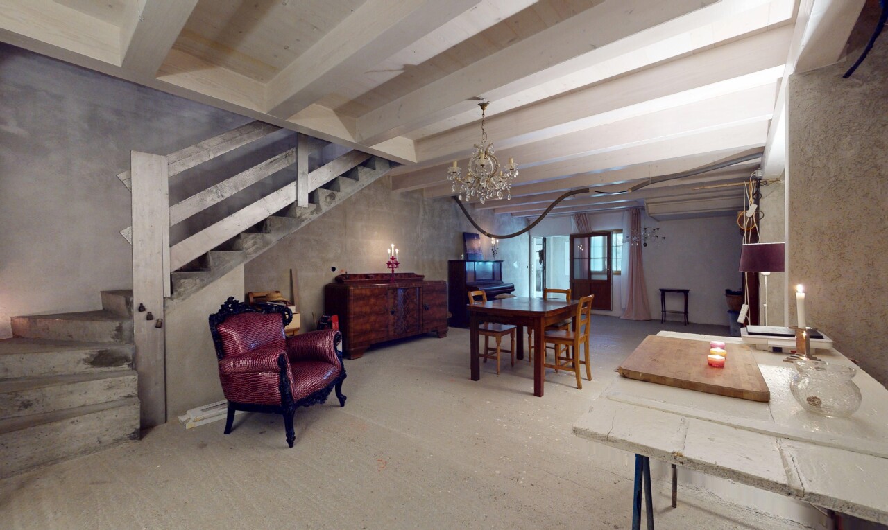 espace intérieur avec poutres apparentes, mur en béton, lustre, et lumière naturelle