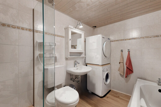 full bathroom featuring tile walls, sink, hardwood / wood-style flooring, and stacked washer and clothes dryer